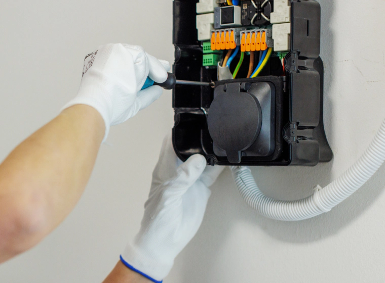 worker installing an ev charger system on a white wall
